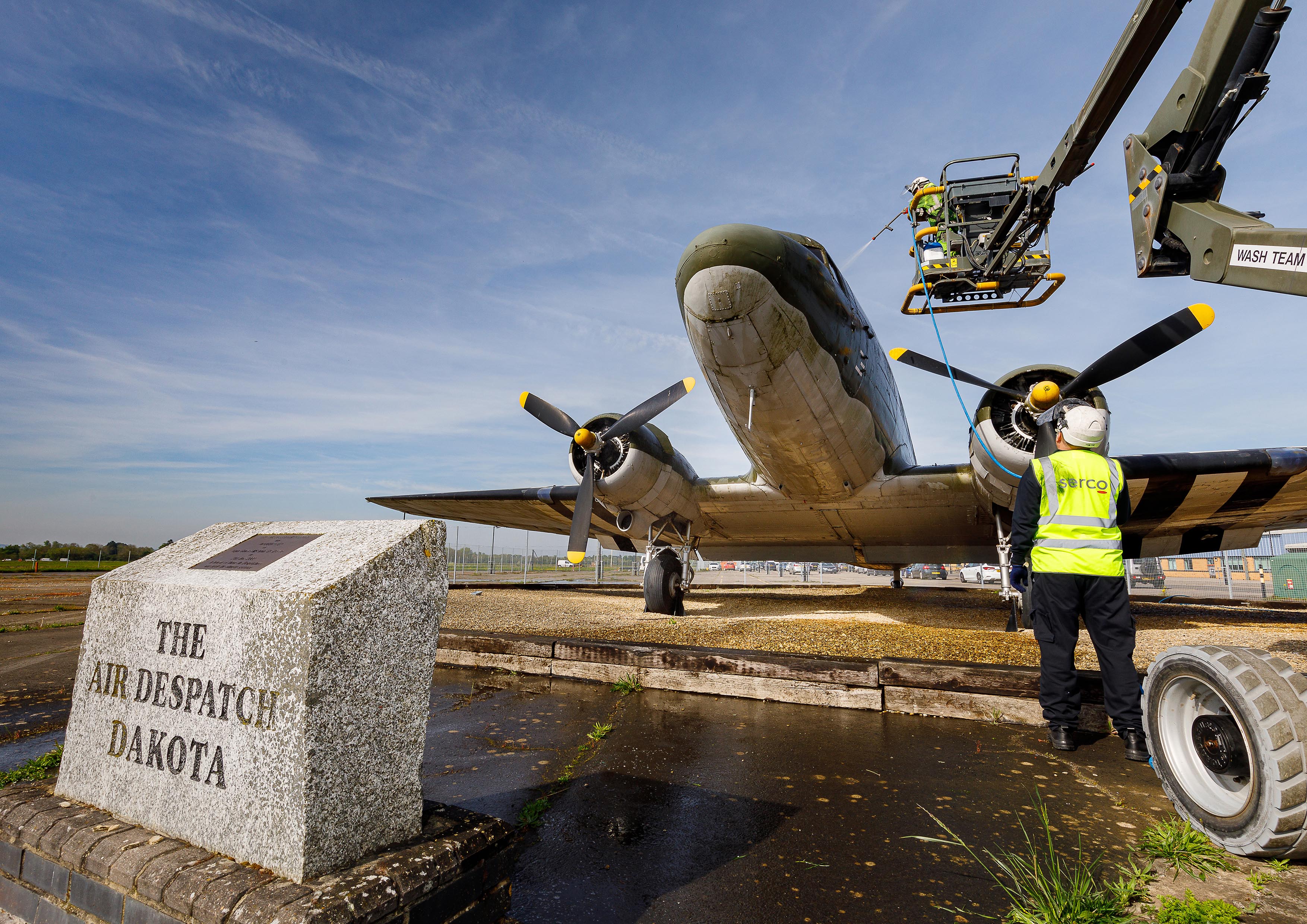 Photo: The Dakota aircraft rests behind its memorial stone and plaque as members of the Serco Aircraft Wash Team pressure wash the area outside of the flight deck